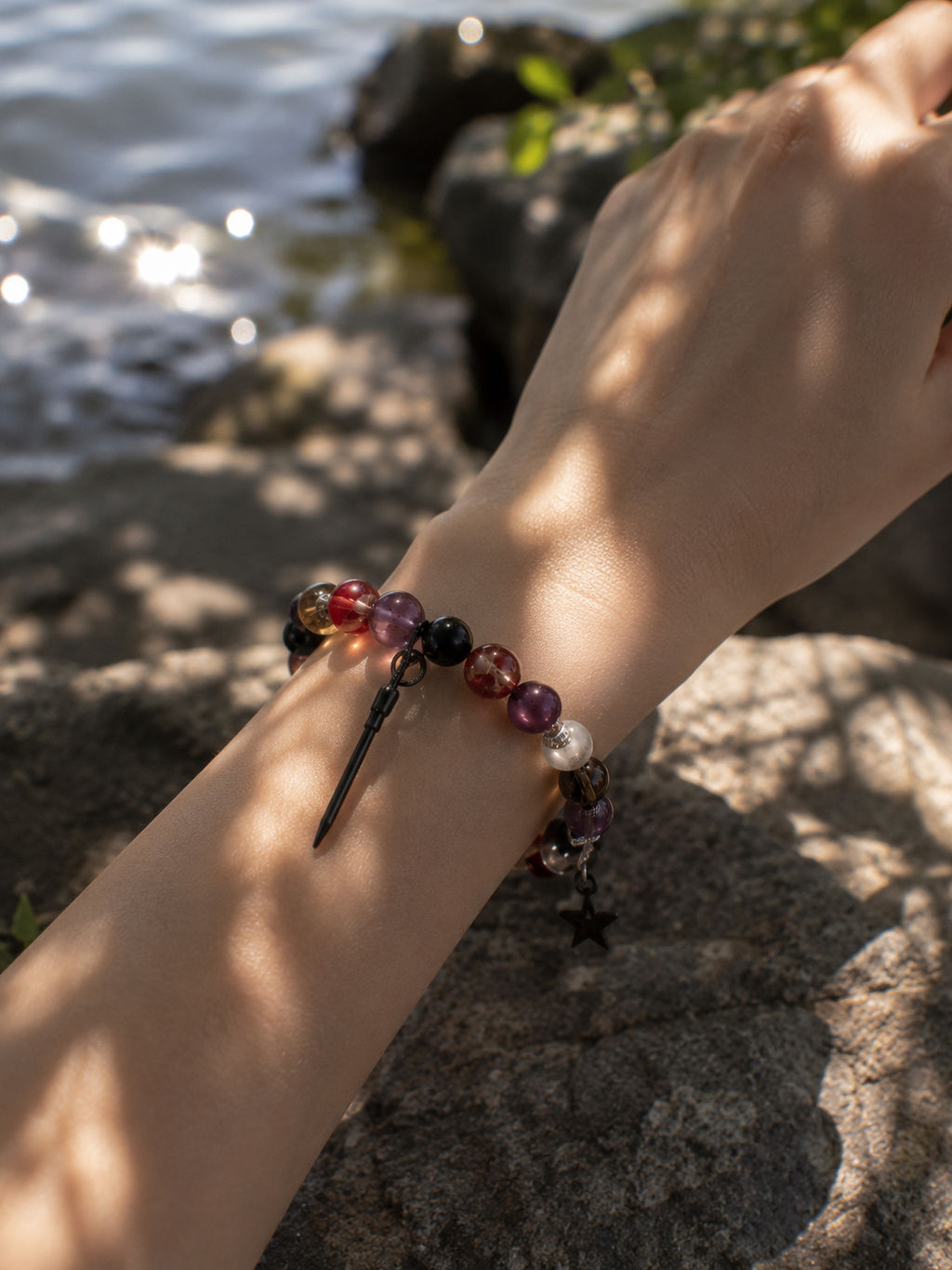 Twilight Bracelet with wine-red, violet, black and clear beads and dangling charms worn on a wrist.